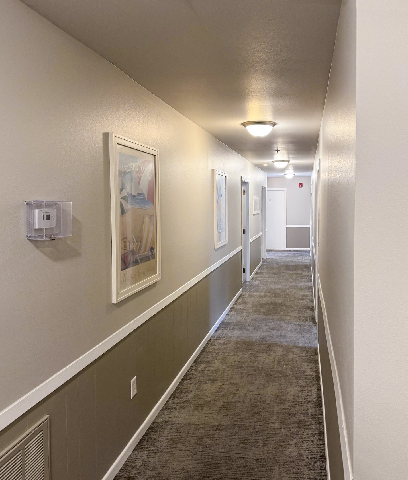 A long hallway with a carpeted floor and white walls.